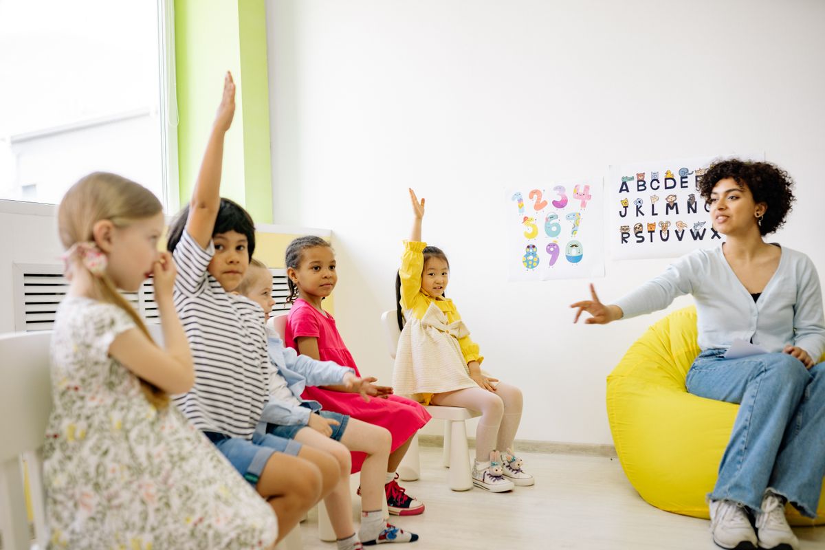 Preschool children raising their hands in a bright classroom at Little Lotus Early Learning Centre in Hyderabad